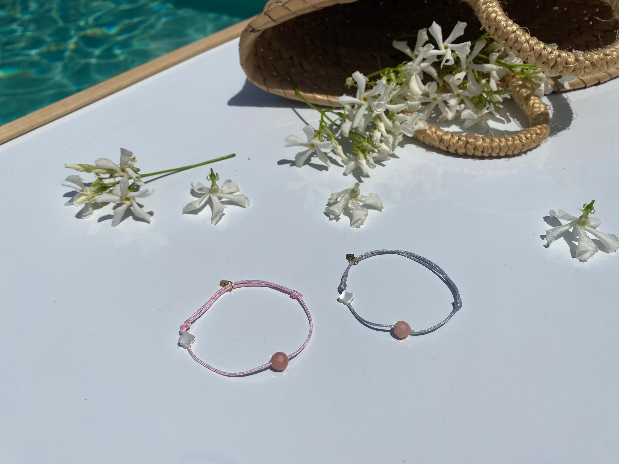Deux bracelets Galatée au bord d'une piscine, entre des fleurs de jasmin